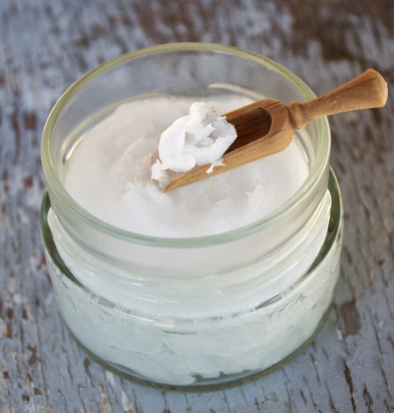Pot d'huile de coco avec une cuillère en bois